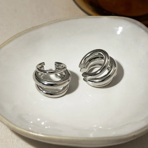 Sculptural silver ear cuff and hoop earrings with layered design.
