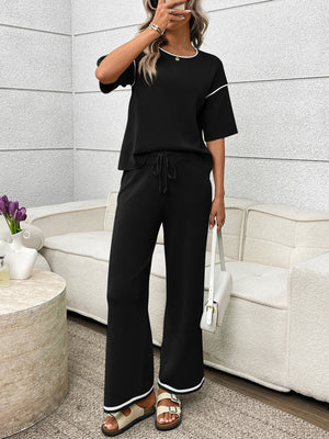 Black loungewear set with crew neck top and drawstring pants, detailed with white piping.