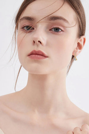 Gold drop earrings with clear prism pendant, delicate chain detail.