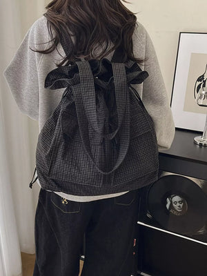 Grey plaid drawstring backpack with adjustable straps and a cinched top closure.