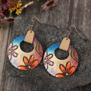Painted floral wood hoop earrings with orange blooms and blue sky accents.