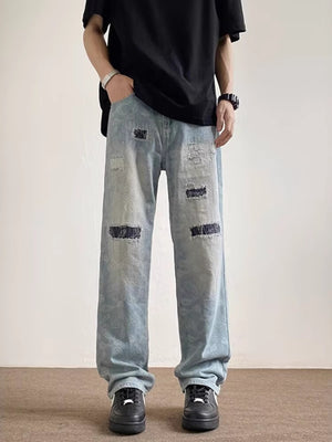 Men's light wash distressed wide-leg jeans with a subtle paisley pattern and pocket details.