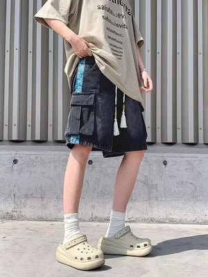 Black denim cargo shorts with braided drawstring and blue side stripe detail.