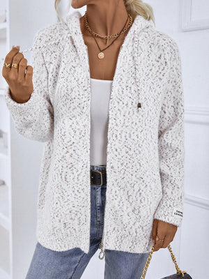 Textured knit zip-up cardigan in white with speckled pattern, drawstring hood, and logo detail on sleeve.