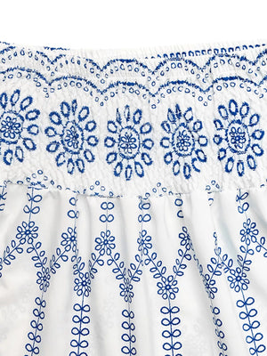 Bohemian maxi skirt with white fabric and blue floral embroidery detail.