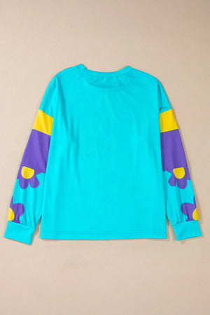 Crewneck long sleeve top in pastel blue with colorblock sleeves featuring purple and yellow daisy print.