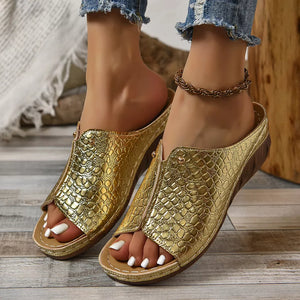 Gold glossy crocodile-embossed wedge sandals with open toe and comfortable sole.