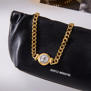Gold curb chain necklace with vintage coin charm detail on black leather.