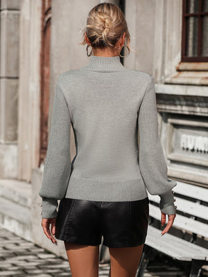 Gray turtleneck knit sweater with pearl button cuffs and ribbed details.