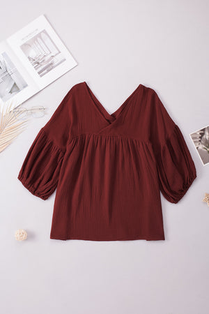 Textured gauze blouse in burnt coral with V-neck and gathered balloon sleeves.