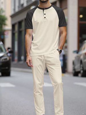 Men's beige loungewear set with a black raglan sleeve henley shirt and drawstring pants.
