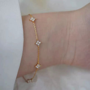 Gold delicate bracelet with four-leaf clover charms and sparkling stones.