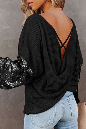 Black waffle knit top with sequin sleeves and criss-cross back detail