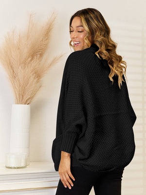 Black cocoon knit cardigan with waffle texture and pockets, acrylic material.
