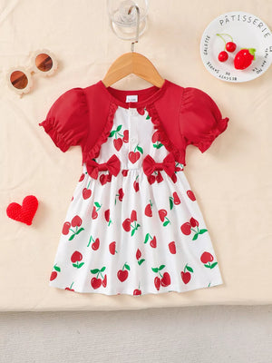 Baby dress with red cherry print, ruffled neckline, short sleeves, and bow details.
