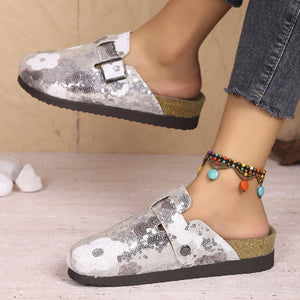 Sparkling sequin slip-on mules in white with decorative buckle detail.