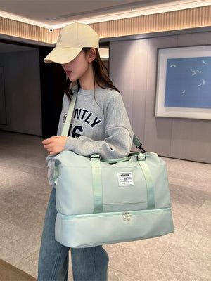 Light green duffel bag with two zippered compartments and green straps, worn by a woman.