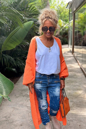 Orange maxi knit cardigan with wide sleeves worn open over a white tank top and distressed jeans.