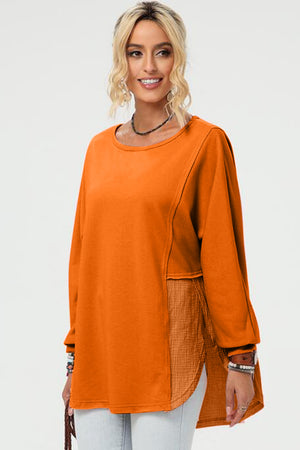 Tangerine split-panel sweatshirt with asymmetric hemline and textured fabric inset