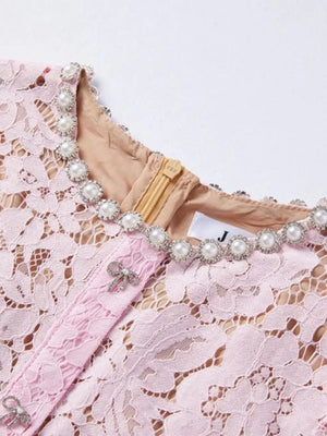 Powder pink lace dress with pearl neckline and bow details.