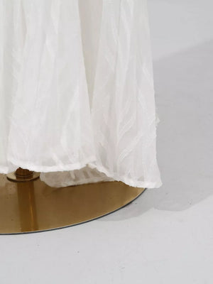 White maxi dress with textured leaf pattern and balloon sleeves, shown on a gold stand.
