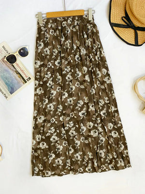 Botanical pleated midi skirt in brown with white floral print, crinkled fabric, and elastic waist.
