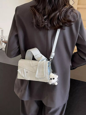 Artisanal mini denim crossbody bag in off-white with adjustable strap and fluffy charm.