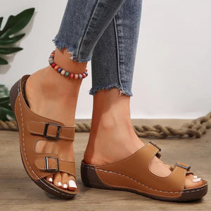Dark brown dual buckle mid-wedge sandals with adjustable straps and white stitching.