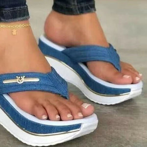 Blue denim platform sandals with elegant emblem detail and white sole.