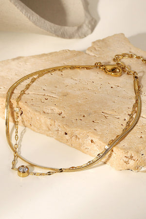 Gold double-strand pavé charm bracelet with a single clear stone detail.