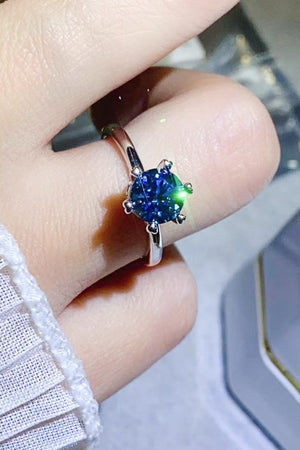 Blue moissanite ring with six-prong setting on a finger
