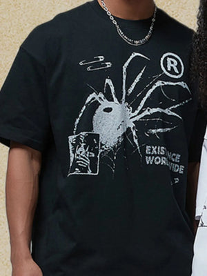 Black oversized graphic tee with spider print, safety pins, and text.
