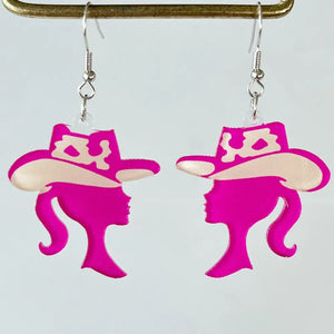Cowgirl silhouette acrylic drop earrings in hot pink with cream accents.