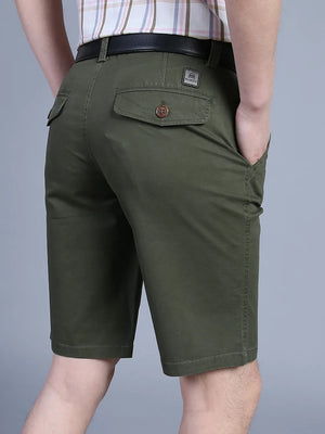 Men's military green chino shorts with button-flap back pockets and a belted waist.