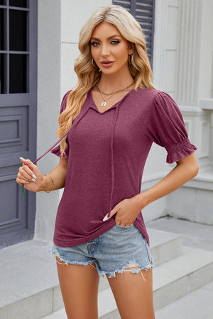 Red-violet tee with puffed sleeves and tie-neck detail.
