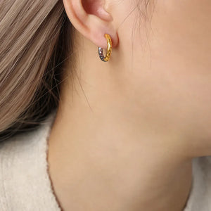 Textured two-tone gold huggie hoop earrings with a hammered finish.