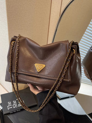Brown shoulder bag with flap and gold chain detail.