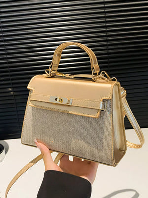 Gold glitter textured mini crossbody bag with top handle and turn-lock closure.
