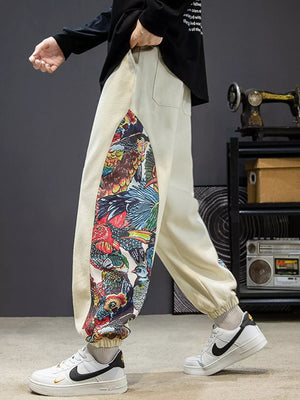 Men's off white joggers with vibrant bird print side panels and elastic cuffs.