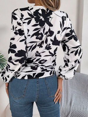White floral knot-front blouse with ruffled cuffs and long sleeves.