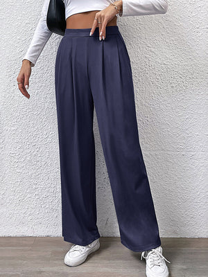 Navy pleated front wide leg trousers with a high waist, styled casually.