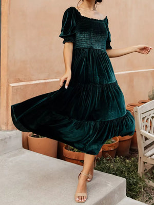 Velvet smocked midi dress in deep teal with ruffled sleeves and tiered skirt.