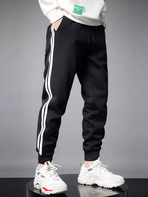 Black cotton joggers with white side stripes and cuffed ankles.