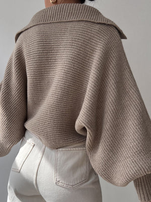 Tan knit sweater with wide collar and balloon sleeves, ribbed texture.