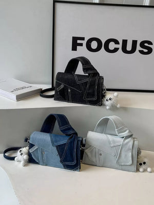 Artisanal denim crossbody bag in black, light blue, and off-white with contrast stitching and a fluffy charm.