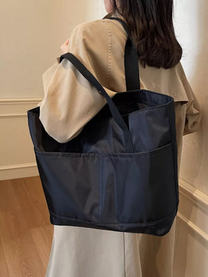 Black Oxford cloth shoulder tote bag with exterior pockets and black straps.