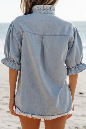 Light blue denim blouse with ruffled collar, puff sleeves, and frayed hem.
