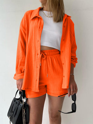 Orange textured gauze button-down shirt and drawstring shorts set with white crop top.