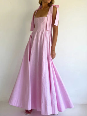 Pink maxi dress with bow-tie shoulder straps and a square neckline.