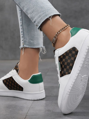White canvas court sneakers with brown patterned panels and green heel accents.